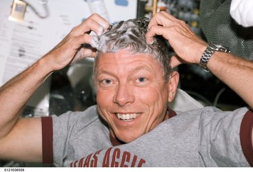 Astronaut Michael E. Fossum washes his hair on the middeck of the Space Shuttle Discovery