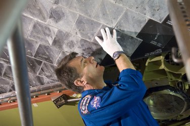 Paolo Nespoli inspects Discovery's heat resistant tiles during CEIT at Kennedy Space Center